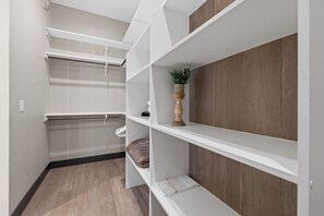 A modern interior with white shelving units, a wooden floor, and a potted plant on one shelf.