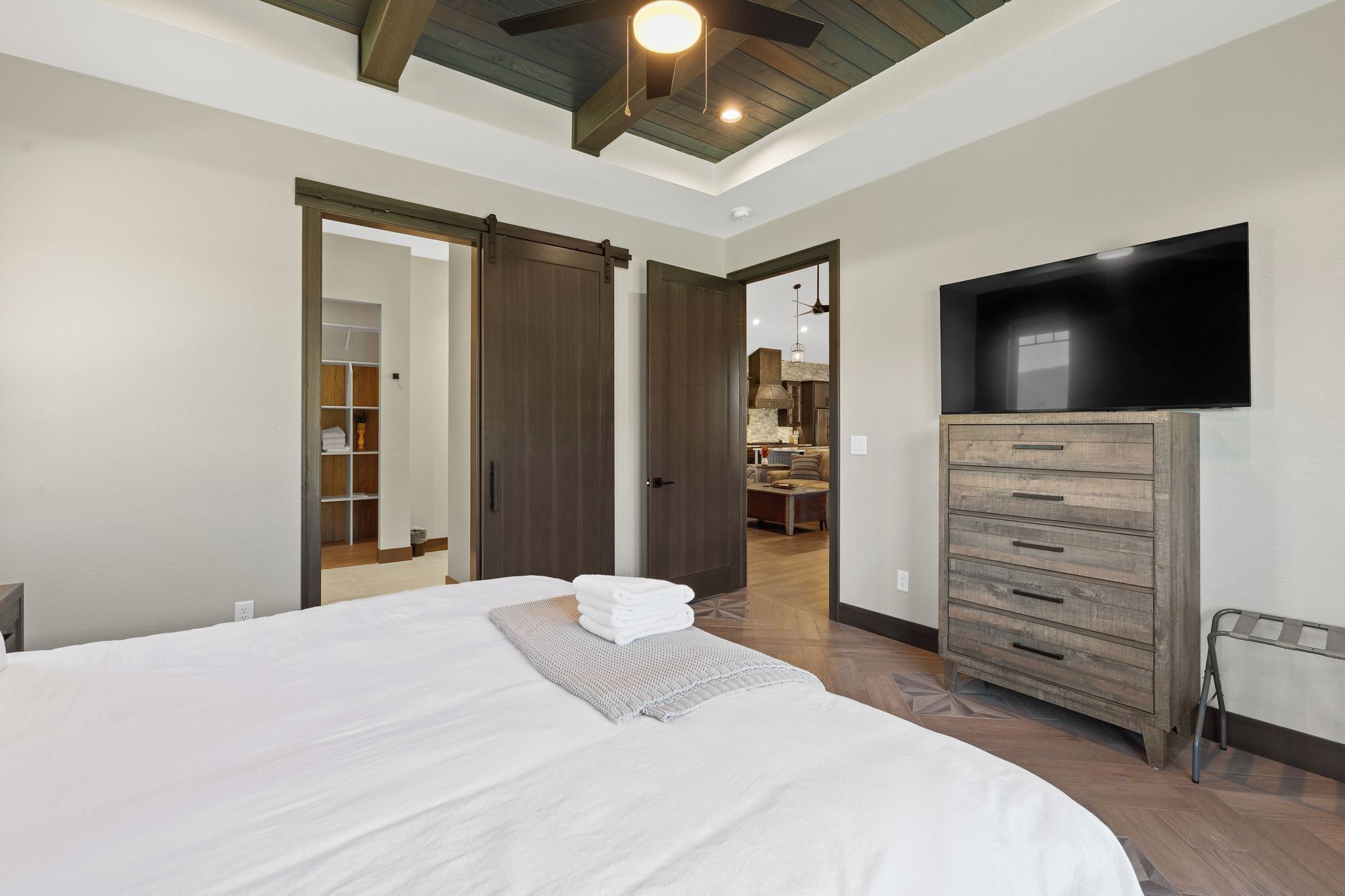 Une chambre à coucher avec un grand lit, une armoire, une télévision et un couloir menant à une salle de bain.