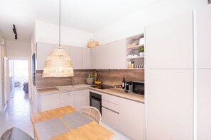 Eine moderne Küche mit einer Holzarbeitsplatte, einer Hängelampe und einem eingebauten Backofen.