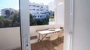 A balcony with a table and chairs, a view of buildings, and a white door. - Design-Apartment mit 2 Balkonen & gehobener Ausstattung (Rodos)