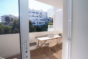 Ein Balkon mit Tisch und Stühlen, Blick auf Gebäude und eine weiße Tür.
