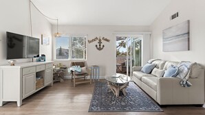 Een moderne woonkamer met een witte bank, een glazen salontafel en een houten vloer.