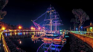 Een groot schip afgemeerd in een haven, met een brug en verlichte gebouwen op de achtergrond.