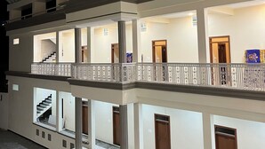 Interior de hotel de varios niveles con un atrio central, escaleras y un balcón con barandillas.