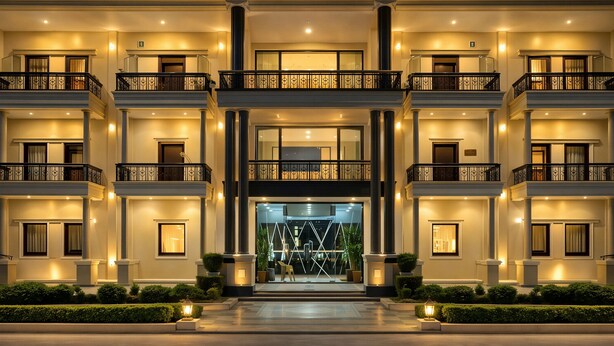 Un hotel de varios pisos con una entrada imponente, balcones y ventanas bien iluminadas.