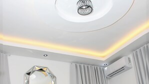 Un dormitorio moderno con un espejo geométrico, un accesorio de iluminación en el techo y un equipo de aire acondicionado.