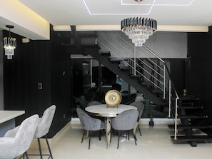 A modern dining area with a chandelier, a staircase, and a view of the living room. - Fabulous 3-bedroom apartment with Jacuzzi in Santiago de los Caballeros.  (Santiago de los Caballeros)