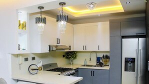 Una cocina moderna con una isla central, electrodomésticos de acero inoxidable e iluminación colgante.