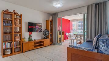 Una sala de estar con un mueble de madera para entretenimiento, un televisor de pantalla plana, un ventilador y un sofá.
