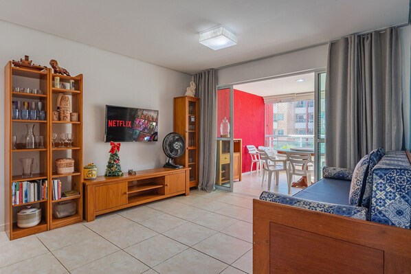 Een woonkamer met een houten tv-meubel, een flatscreen-televisie, een ventilator en een bank.