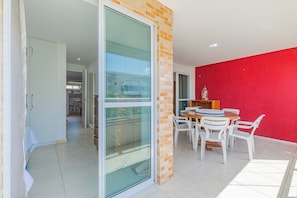 Un appartement moderne doté d’une porte coulissante en verre, d’un coin repas avec une table et des chaises, et d’un mur d’accent de couleur rouge.