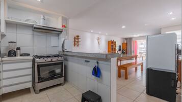 Una cocina moderna con estufa a gas, horno y microondas integrado. Hay un taburete y un banco en la zona de comedor.