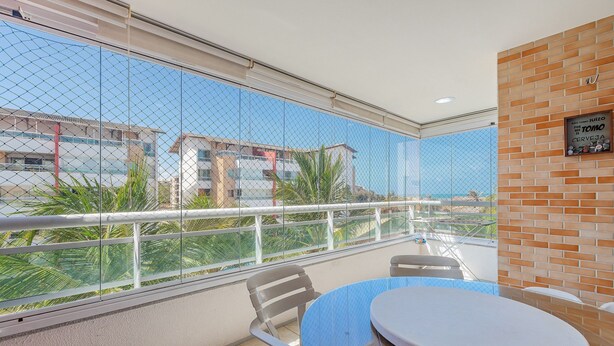 Ein Balkon mit Glasbrüstung, einem runden Tisch und zwei Stühlen.