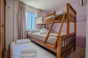 Ein Schlafzimmer mit Etagenbett, Fenster, Vorhängen und einer Tür.