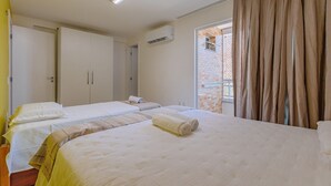 Ein Hotelzimmer mit zwei Betten, einem Fenster mit Vorhängen, einer Klimaanlage und einer Tür.