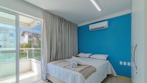 Ein Hotelzimmer mit Bett, einem Vorhangfenster, einer Klimaanlage und Blick auf Gebäude.