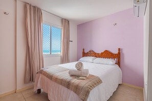 Ein Schlafzimmer mit einem Bett, einem Vorhangfenster und einem Holzkopfteil.