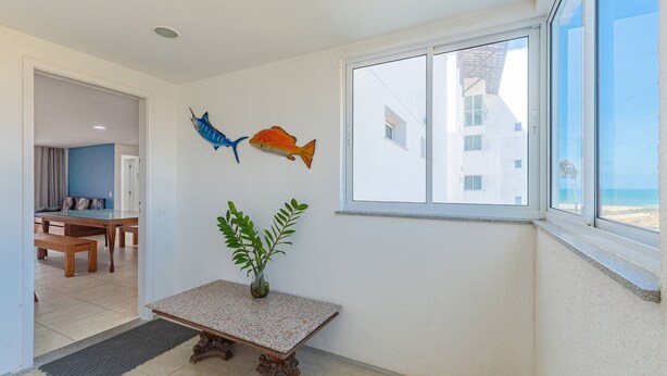 Ein Zimmer mit Esstisch, einer Bank, einer Topfpflanze und zwei Fisch-Wandbildern.