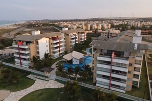 Un quartier résidentiel situé sur la côte, avec des immeubles à plusieurs étages, une piscine et une plage en arrière-plan.