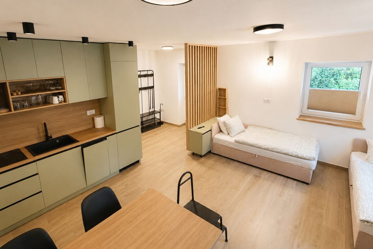 A compact living space with a kitchenette, a dining area, and a bed.