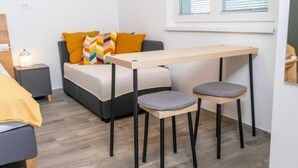 Pieni, moderni huone, jossa on sänky, pöytä, kaksi tuolia ja yöpöytä, jossa on lamppu.