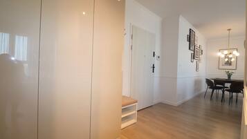 A modern interior with a wooden floor, a white door, a bench, and a dining area with chairs and a table.