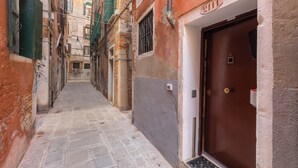 A narrow alleyway with a brown door on the right, flanked by buildings with visible wear and graffiti. - Venice, Ghetto, Campo della Maddalena, Rialto, near train station, Wi-Fi (Venezia)