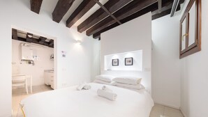 A bedroom with a large bed, white walls, a wooden ceiling, and a small bathroom visible through an open door. - Venice, Ghetto, Campo della Maddalena, Rialto, near train station, Wi-Fi (Venezia)