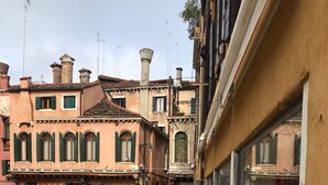 A narrow alleyway with buildings on either side, featuring traditional architecture with arched windows and stone facades. - Venice, Ghetto, Campo della Maddalena, Rialto, near train station, Wi-Fi (Venezia)