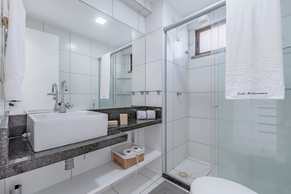 Une salle de bain moderne avec un grand lavabo blanc, une douche en verre et des toilettes blanches.