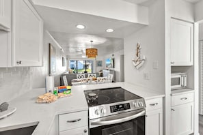 A modern kitchen with white cabinetry, a built-in stove, and a microwave. - Newly Rehabbed • Pickleball/Tennis • Beach Access (Bradenton Beach)