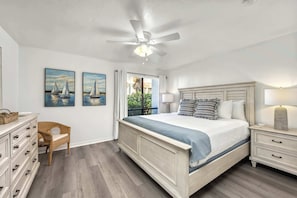 A bedroom with a large bed, a ceiling fan, a nightstand, a dresser, and two paintings on the wall. - Newly Rehabbed • Pickleball/Tennis • Beach Access (Bradenton Beach)