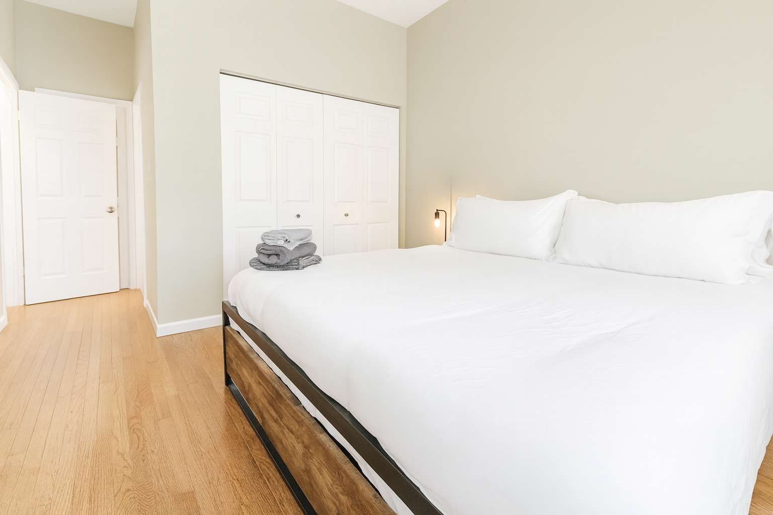 A bedroom with a bed, a wardrobe, and a stack of folded towels.
