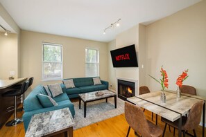 Una sala de estar con sofá, mesa de centro, chimenea, televisor y zona de comedor.