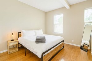 Un dormitorio con cama, mesita de noche, lámpara y un espejo grande.
