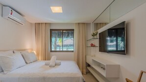 Une chambre d’hôtel équipée d’un lit, d’une télévision, d’une fenêtre avec des rideaux et d’un climatiseur fixé au mur.