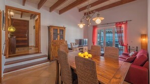 Uma sala de jantar com mesa de madeira, cadeiras de vime e sofá vermelho.