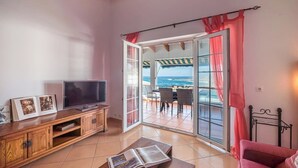 Uma sala de estar com televisão, móvel de entretenimento de madeira e um livro sobre a mesa de centro.