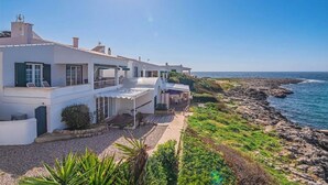Um imóvel costeiro com um edifício branco, um pátio e vista para o mar.
