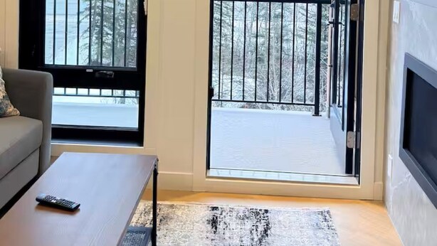 Una sala de estar moderna con un sofá gris, una mesa de centro y un ventanal con vistas a un paisaje nevado.