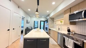 Una cocina moderna con una isla central, electrodomésticos de acero inoxidable y un rincón de comedor con sofá.