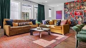 A modern living room with two sofas, a coffee table, and a colorful wall mural. - Sleeps 20: Views, HotTub, FirePit, Grill, Parking (Nashville)