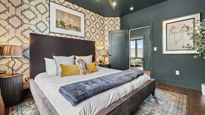 A modern bedroom with a large bed, a headboard, a bedside table, a lamp, and a patterned wall. - Sleeps 20: Views, HotTub, FirePit, Grill, Parking (Nashville)