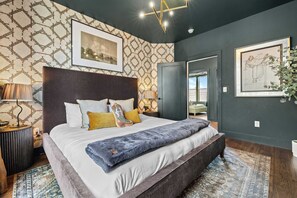 A modern bedroom with a large bed, a headboard, a bedside table, a lamp, and a patterned wall. - Sleeps 20: Views, HotTub, FirePit, Grill, Parking (Nashville)