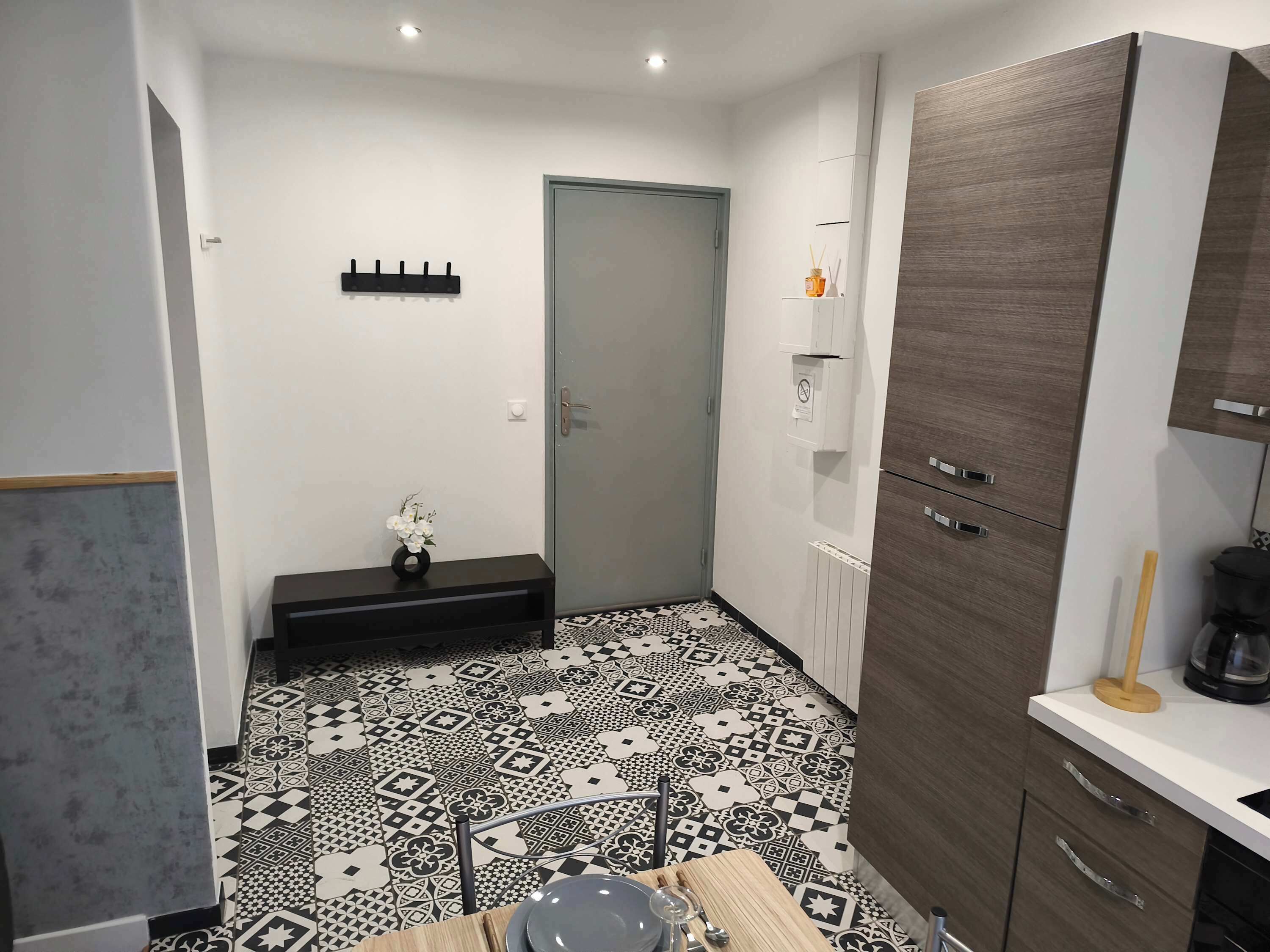 A compact kitchen with a patterned floor, a built-in cabinet, and a coffee maker on the countertop.