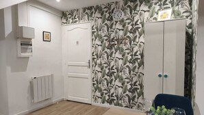 Et værelse med en hvid dør, en radiator, et ur på væggen og et spisebord dækket med tallerkener, glas og en plante.
