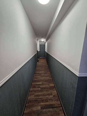 Un pasillo estrecho con suelo de madera oscura y paredes de tonos contrastantes.