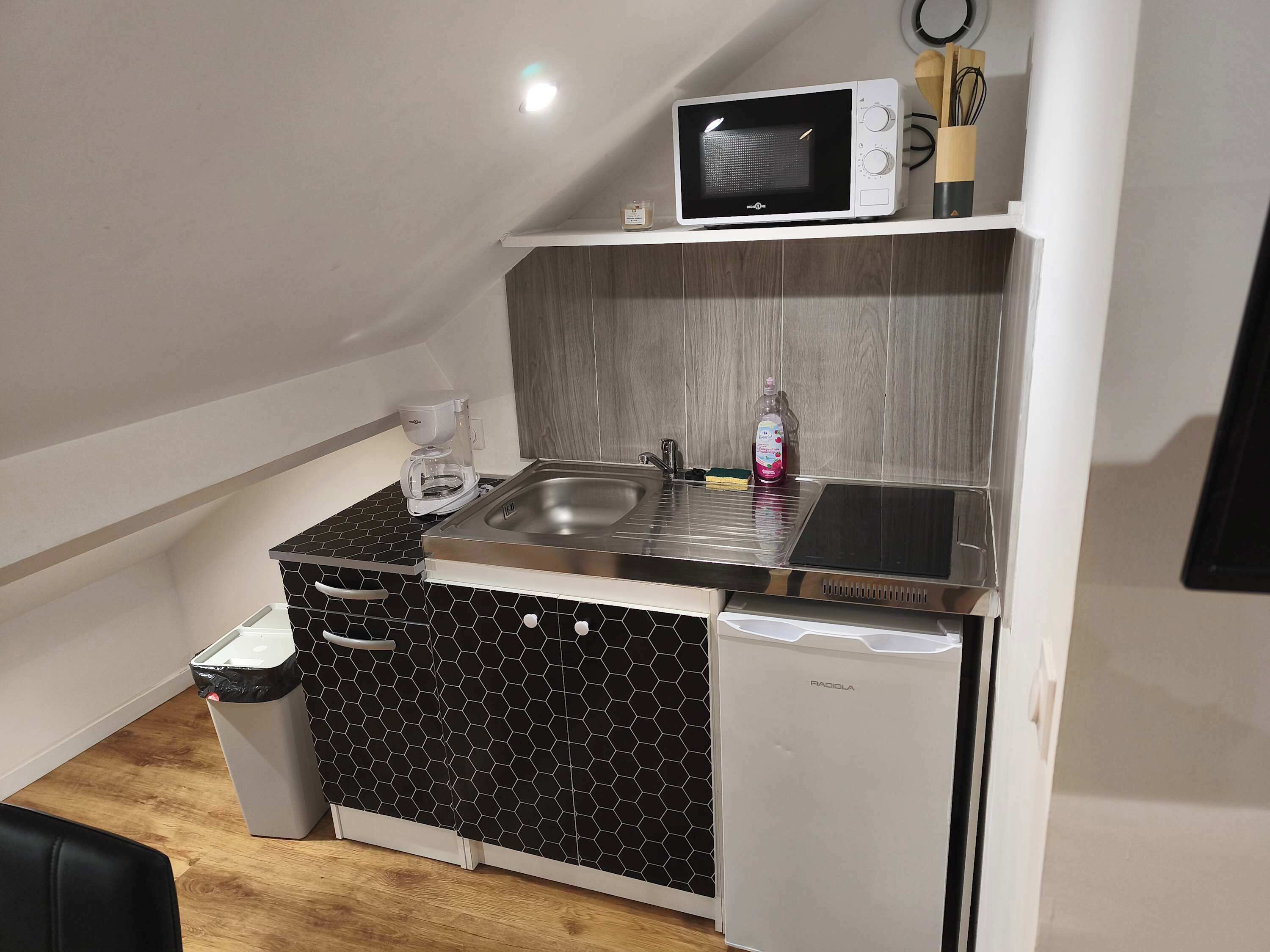 Una kitchenette compacta equipada con microondas, cafetera, pileta y un refrigerador pequeño.