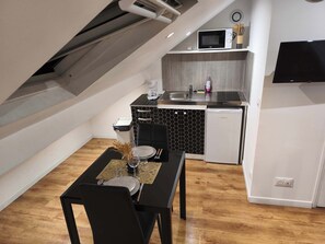 Une cuisine compacte équipée d’un four à micro-ondes, d’un évier et d’un lave-vaisselle. On y trouve une table à manger, mise avec des assiettes, des verres et des couverts.