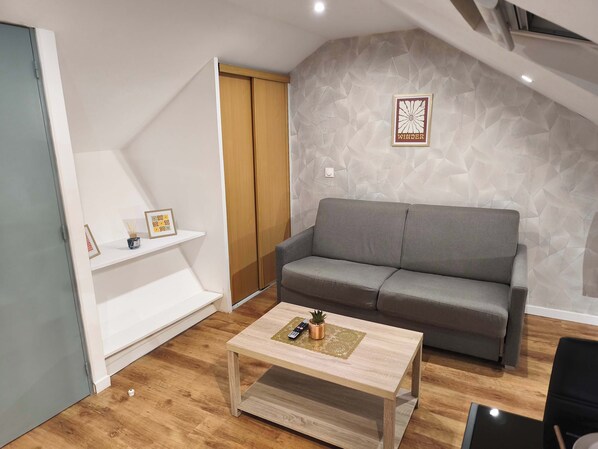 Un salon moderne avec un canapé gris, une table basse en bois et un cadre photo fixé au mur.